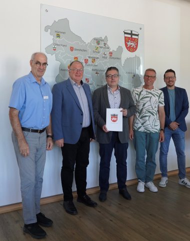 Dienstjubiläum In der Mitte hält Jürgen Neiß ein Dokument mit einem Wappen, das ihm zu seinem 25-jährigen Dienstjubiläum überreicht wurde. Bürgermeister Guido Nisius steht links neben ihm und gratuliert. Links außen steht Bernhard Jüngling, Fachbereichsleiter für Organisation und Verwaltungssteuerung sowie Personalleiter. Rechts von Neiß stehen Dirk Hansen, Fachbereichsleiter für Ordnung, Soziales und Schulen, sowie Tim Schneider vom Personalrat.