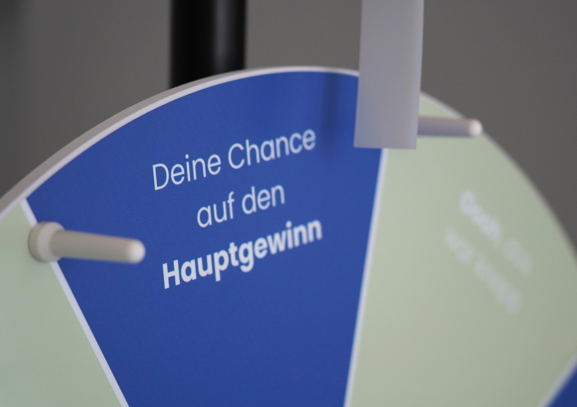 Nahaufnahme eines blau-grünen Glücksrads. Auf einem blauen Segment steht der Text „Deine Chance auf den Hauptgewinn“. Ein Zeiger zeigt auf das Rad. Das Bild wirbt für eine Gewinnspielaktion beim Heimatfest.
