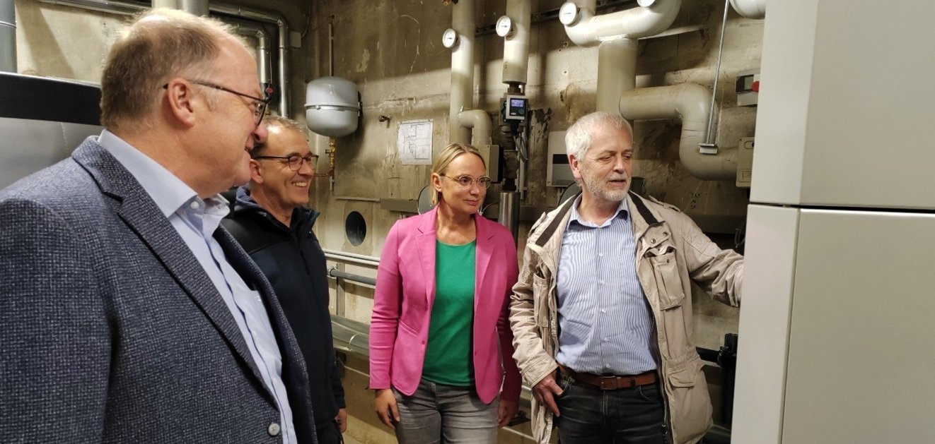 Im Rahmen eines Ortstermins in der Grundschule Wershofen erklärt Herr Pertz vom Ingenieurbüro Pertz (re.) die neue Pelletheizungsanlage. Die Anlage ersetzt die bisherige Ölheizung und trägt durch eine deutliche Reduzierung des CO₂-Ausstoßes zur nachhaltigen Verbesserung der Energieeffizienz der Schule bei. Die Erläuterungen richten sich an Bürgermeister Guido Nisius (li.), Hausmeister Guido Theisen (2. v. li.) sowie Schulleiterin Katja Seibel (2. v. re.).