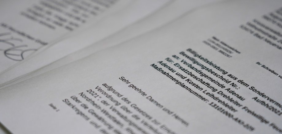 Förderbescheid über 1,27 Mio. Euro Mehrere Blätter eines offiziellen Dokuments liegen leicht überlappend auf einem Tisch. Das Schreiben trägt den Titel „Bewilligungsleistung aus dem Sondervermögen“ und richtet sich an die Verbandsgemeinde Adenau zur Ersatzbeschaffung einer Drehleiter für die Freiwillige Feuerwehr Adenau.