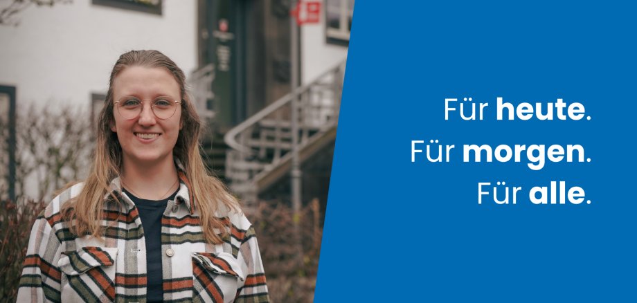 Porträt von Frau Henschel, neuer Mitarbeiterin der Verbandsgemeindeverwaltung. Sie steht lächelnd im Freien vor einem Gebäude. Rechts im Bild ist ein blauer Bereich mit dem Text „Für heute. Für morgen. Für alle.“ zu sehen.