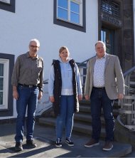 Begrüßung einer neuen Mitarbeiterin in der Verbandsgemeindeverwaltung Adenau Drei Personen stehen nebeneinander vor einem Verwaltungsgebäude.