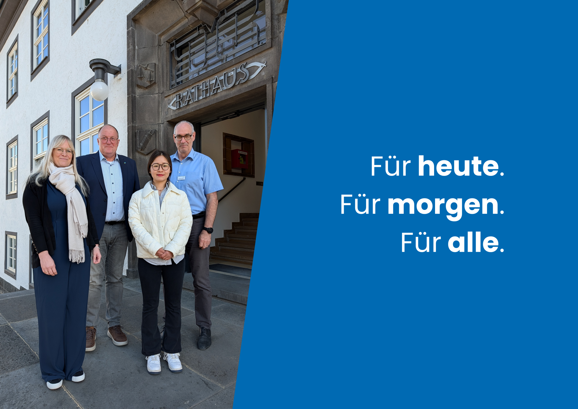 Vier Personen stehen nebeneinander vor einem Verwaltungsgebäude.